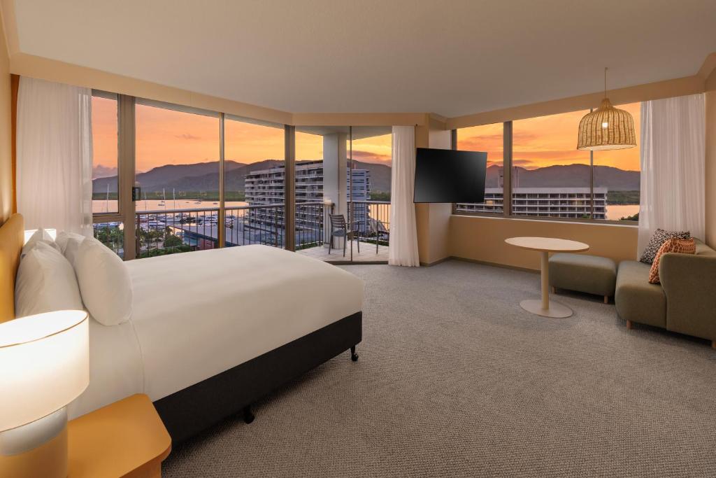 a hotel room with a large bed and a view at Pacific Hotel Cairns in Cairns
