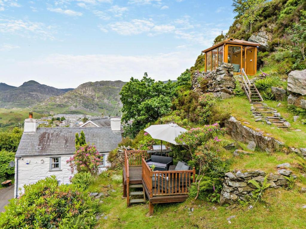 a house on a hill with a bench and an umbrella at 3 Bed in Fucheswen oc-c29607 in Blaenau-Ffestiniog
