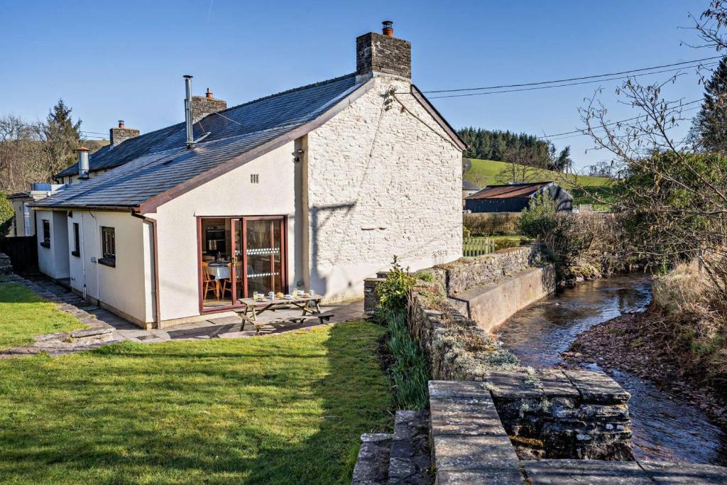 a white cottage with a river in front of it at 3 Bed in Pentre Bach oc-t30863 in Pentre-bâch