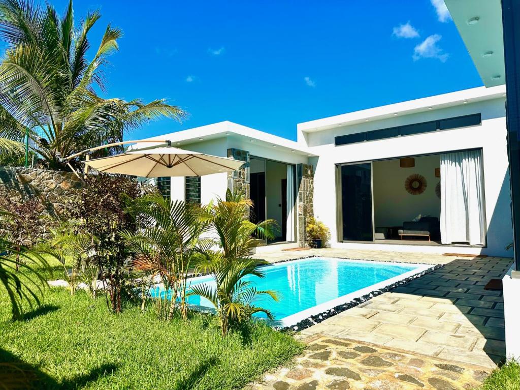 a villa with a swimming pool and an umbrella at Résidence Azélina 2 in Pointe aux Canonniers