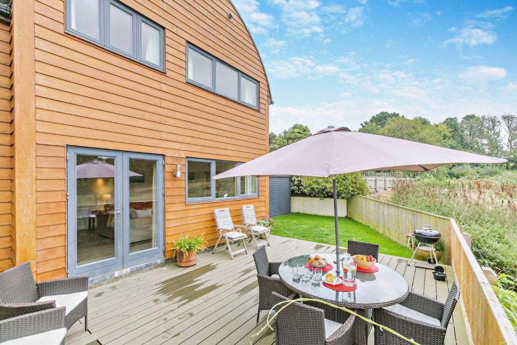 a wooden deck with a table and an umbrella at 3 Bed in Goldenbank oc-c29977 in Falmouth