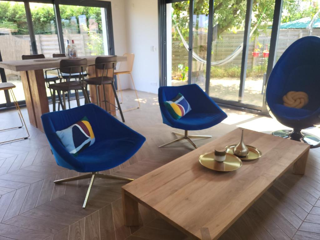 a living room with two blue chairs and a wooden table at Maison familiale in Le Teich