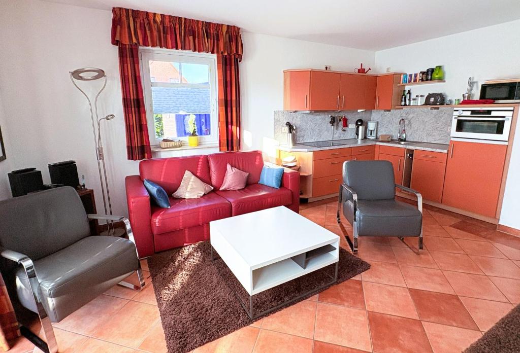 a living room with a red couch and a table at Ferienhaus Carlo - renoviert 2025, top Lage, hundefreundlich in Glowe