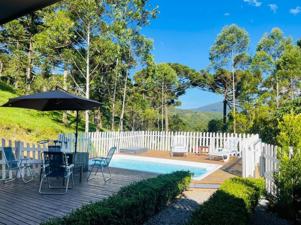 a patio with a table and chairs and an umbrella at Pousada Reserva Verde com piscina privada com vista para a serra Studio térreo in Quatro Barras