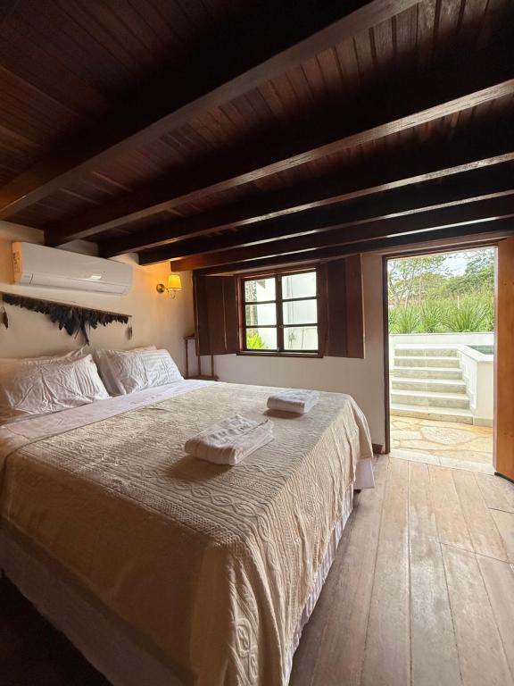 a bedroom with a large bed and a large window at Casa Sol Piscina e Cachoeira in Pirenópolis