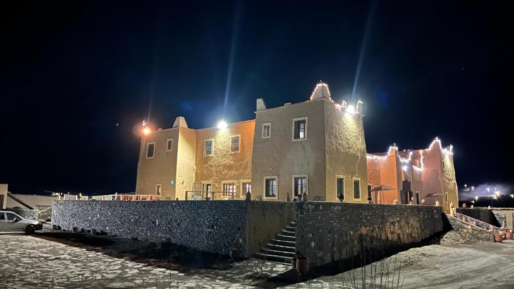 a large building with stairs in the snow at night at Kasbah Restaurant Citoyenne in Agoudal