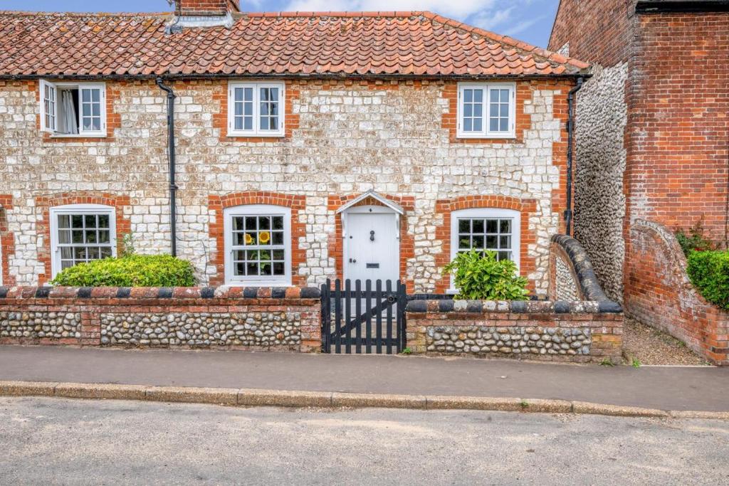 a brick house with a white door and a stone wall at 2 Bed in Burnham Overy Staithe oc-p30460 in Burnham Market