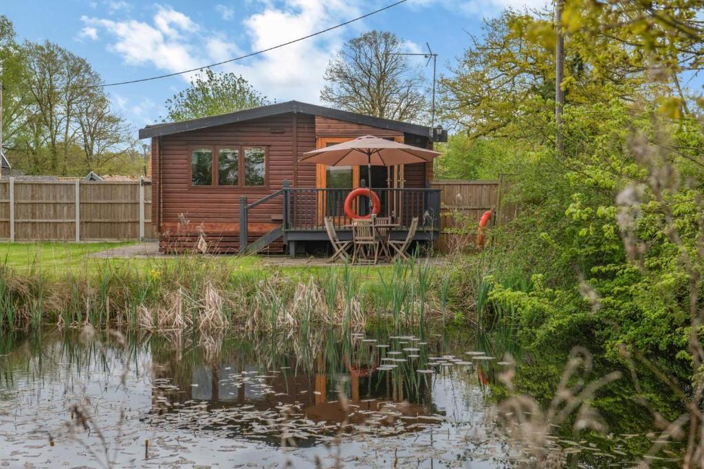 a cabin by a pond with an umbrella at 2 Bed in Otley oc-slm in Burgh