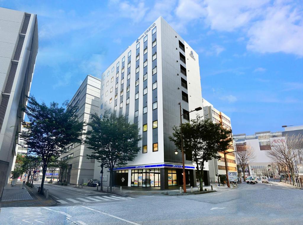 a tall white building on a city street at Hotel Trend Okayama Ekimae in Okayama