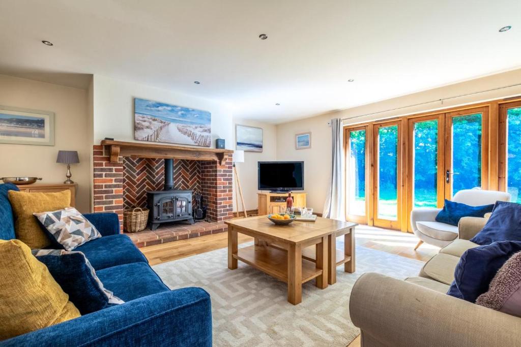 ein Wohnzimmer mit blauen Sofas und einem Kamin in der Unterkunft 3 Bed in Fakenham oc-1315 in Thursford