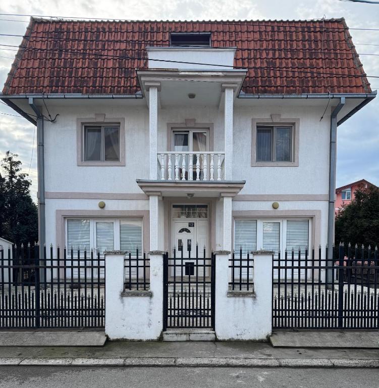 a white house with a fence in front of it at Rooms Jajinci in Belgrade