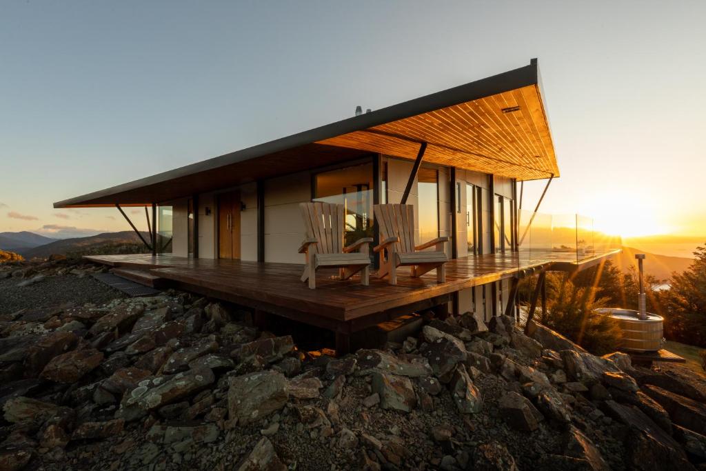 a house on a hill with two chairs on a deck at Peak View Retreat in Nelson