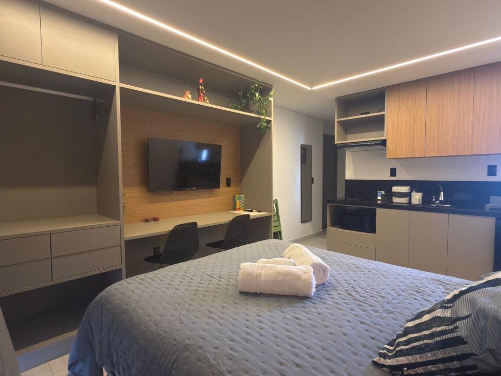 a bedroom with a bed with a desk and a television at Lindo Studio com rooftop e piscina in Cabedelo