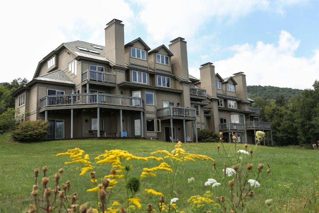 a large house on a hill with a field of flowers at Solitude Village at Okemo by Vail Resorts in Ludlow