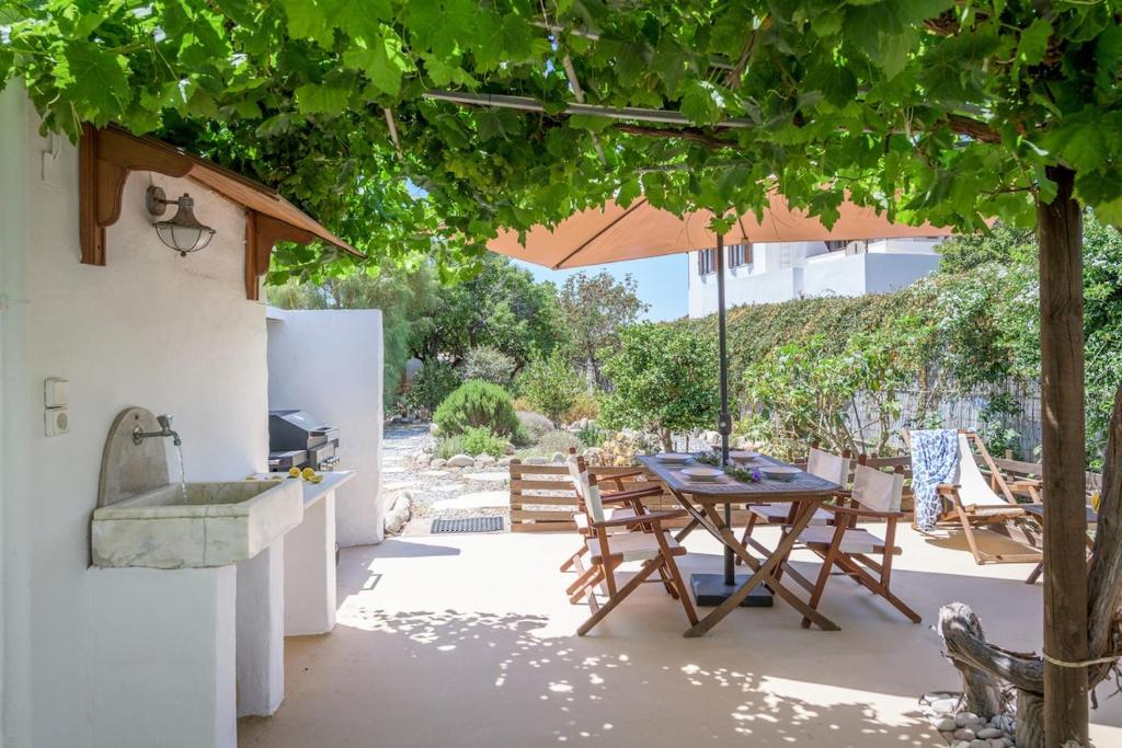 a patio with a table and an umbrella at Casa de Flores 1 in Plaka Milou