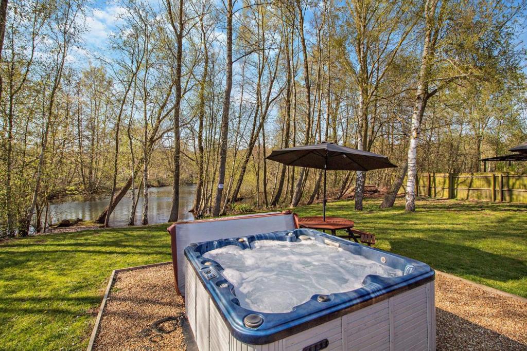 a hot tub in a yard with an umbrella at 5 Bed in Pentney oc-w27337 in Pentney