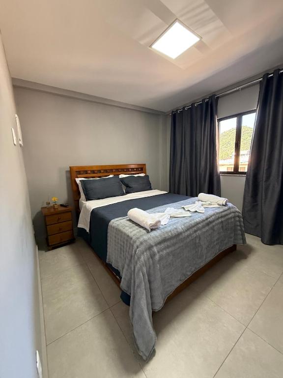 a bedroom with a bed with blue sheets and a window at Serra Premium Residence in Petrópolis