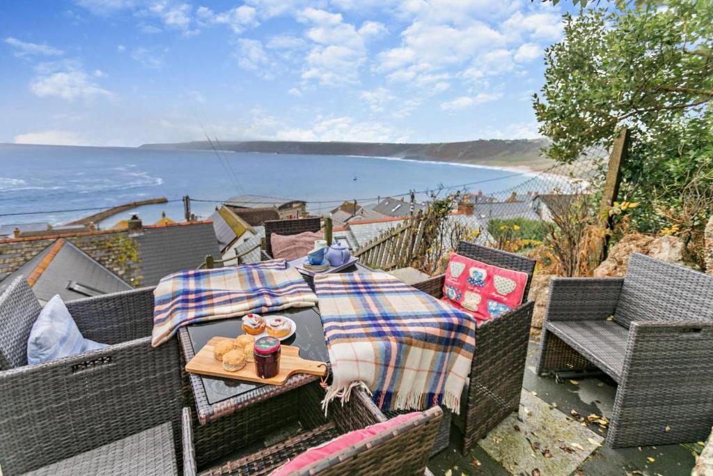 a patio with a table and chairs with a view of the ocean at 3 Bed in Sennen Cove oc-c29670 in Sennen