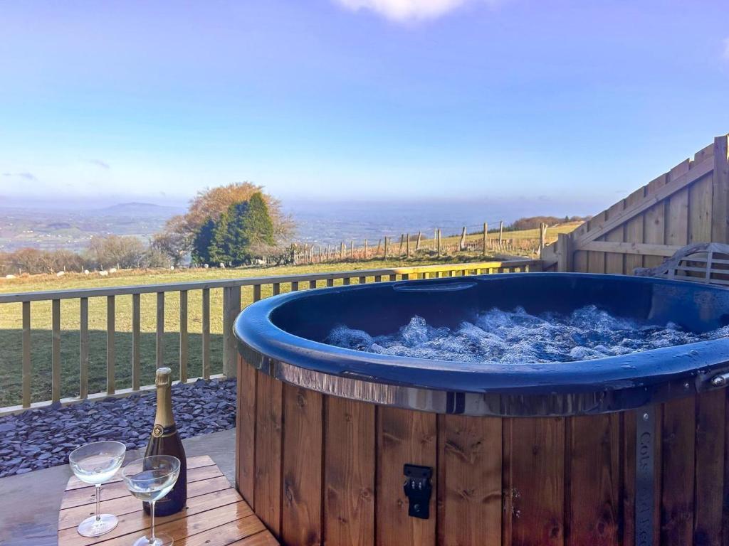 a barrel hot tub with a bottle of wine and wine glasses at 1 Bed in Llanover oc-y30114 in Llanover