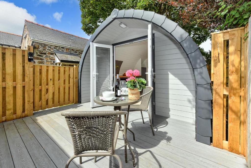 a small grey shed with a table and chairs on a deck at 1 Bed in Abersoch oc-thepod in Abersoch