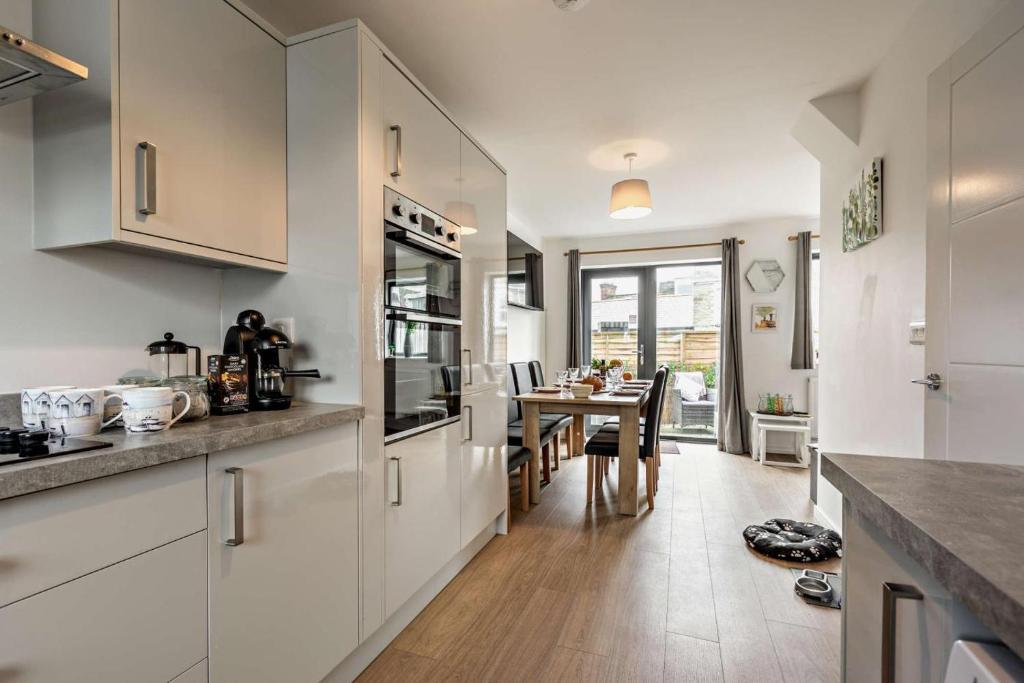 a kitchen with white cabinets and a dining table at 3 Bed in Ilfracombe oc-s29585 in Ilfracombe