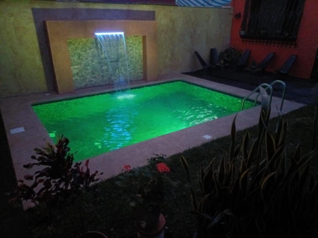 a swimming pool with a waterfall in a yard at night at Flor de Cera in Tepoztlán