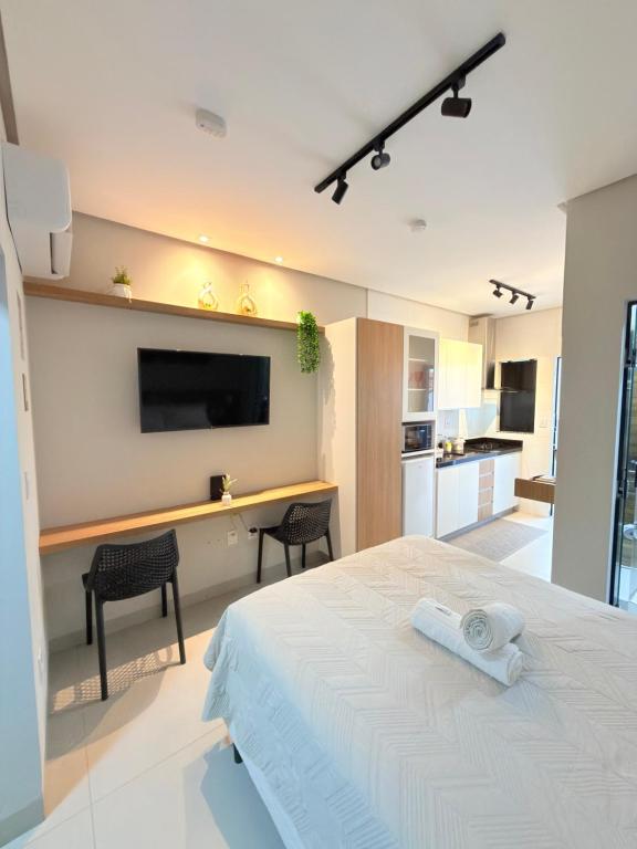 a bedroom with a bed and a desk with a television at Flat Executivo, Moderno e Aconchegante - Ahava Stays in Montes Claros