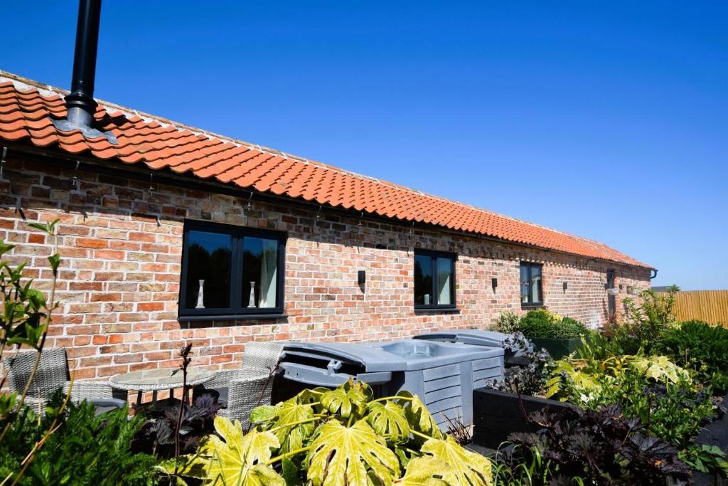 a brick house with a hot tub in a garden at 1 Bed in Saltfleetby oc-b30073 in Saltfleetby Saint Peter