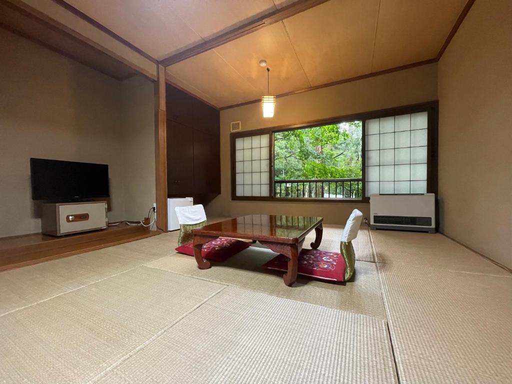 a living room with a table and a tv at Shibu Tatunokan in Chino