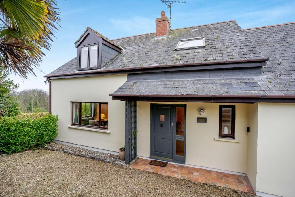a white house with a black door and windows at 4 Bed in Tenby oc-vv27177 in Manorbier