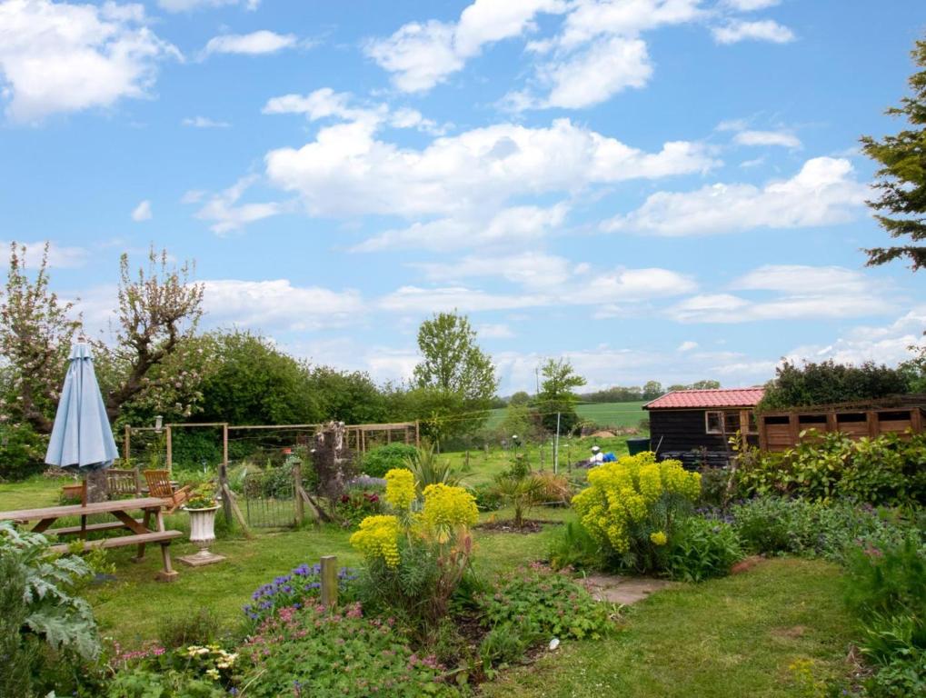 a garden with a table and a umbrella and flowers at 2 Bed in Long Melford oc-9ws in Long Melford