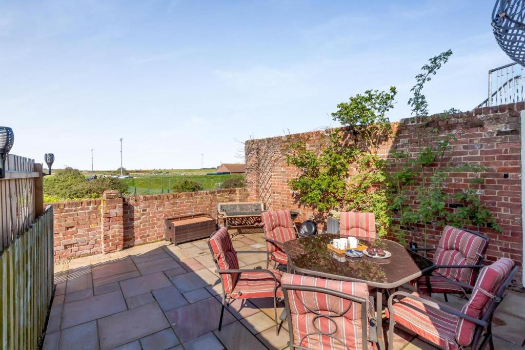a patio with a table and chairs and a brick wall at 2 Bed in Wells-next-the-Sea oc-2032 in Wells next the Sea