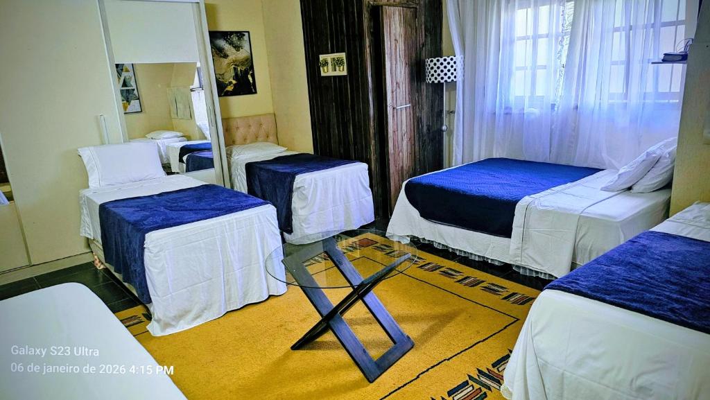 ein Hotelzimmer mit drei Betten und einem Spiegel in der Unterkunft Mimi Nova in Osório