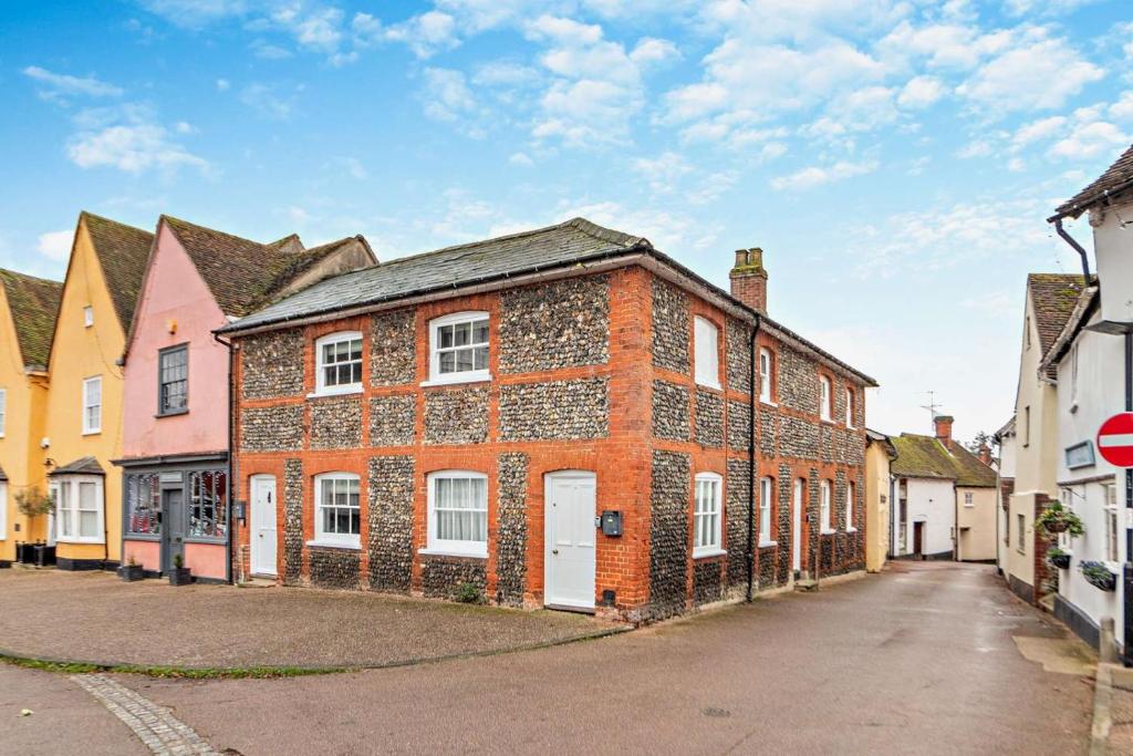 a red brick building with white doors on a street at 2 Bed in Lavenham oc-t30056 in Lavenham