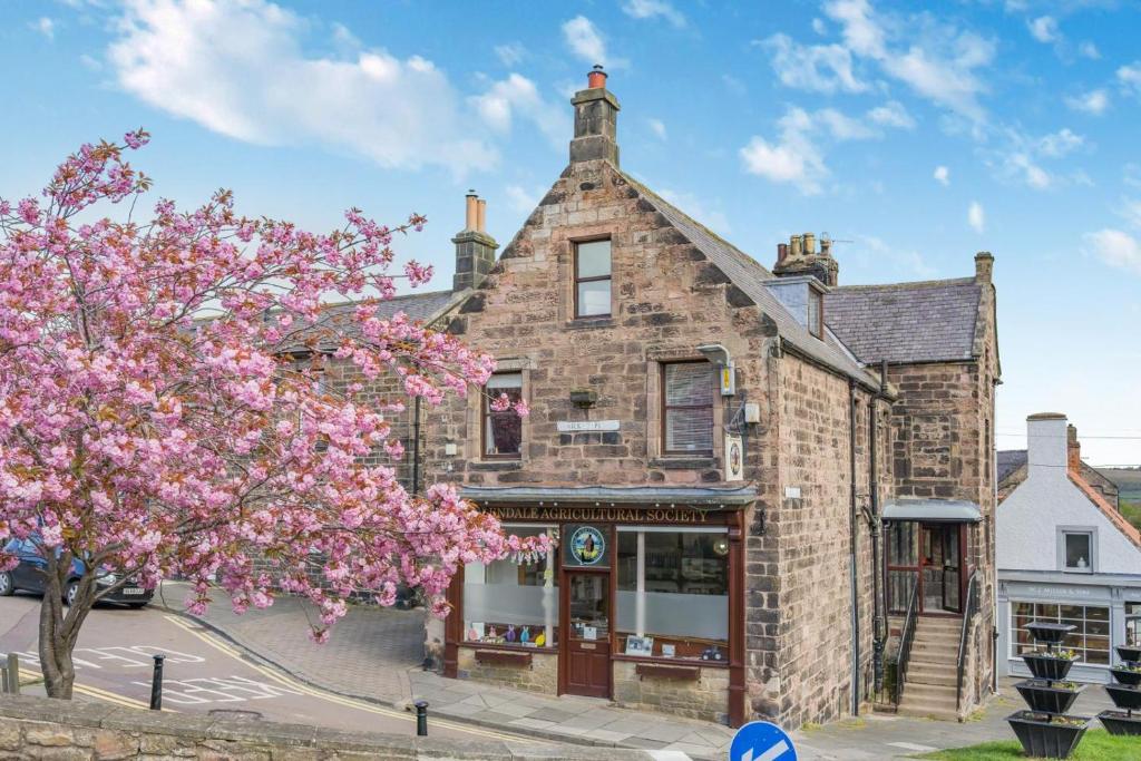 an old brick building with a tree in front of it at 3 Bed in Wooler oc-m31820 in Wooler