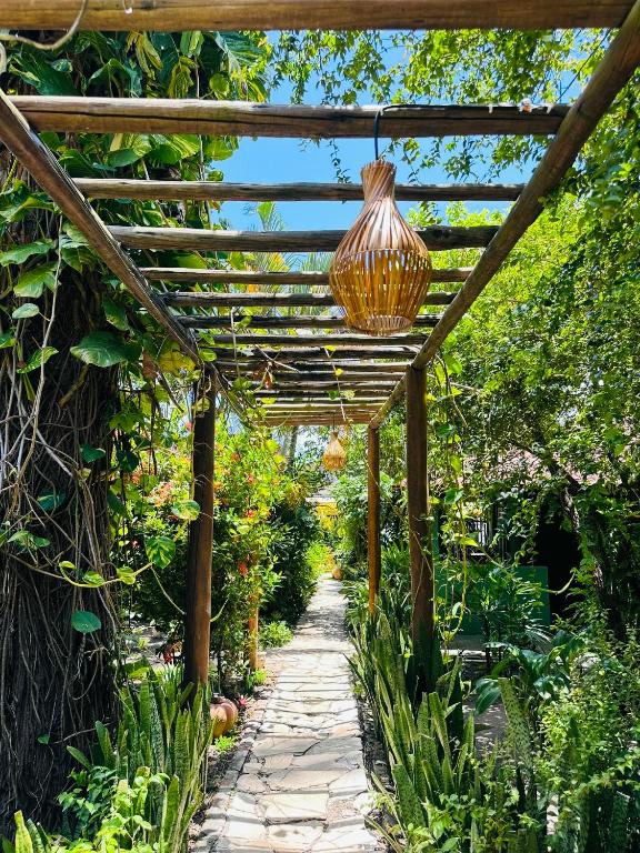 a pergola in a garden with a hanging light at Pousada Sossego Boipeba in Ilha de Boipeba