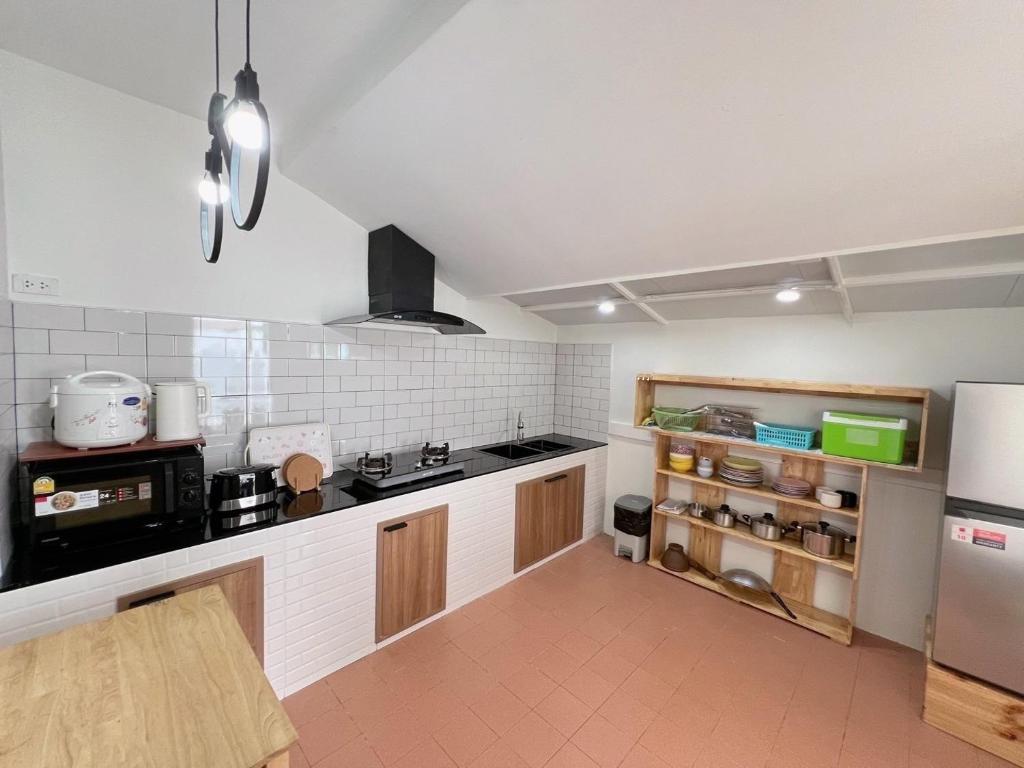a kitchen with a stove and a refrigerator at แสงจันทร์พลูวิลล่าระยอง in Ban Thung Haeo