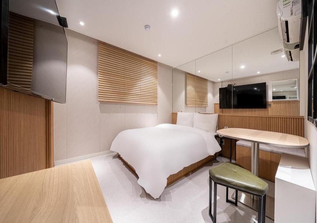 a bedroom with a bed and a table and a kitchen at Hotel Salmon in Seoul