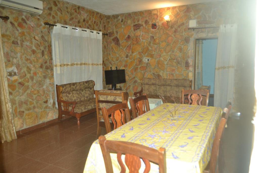 a dining room with a table and chairs and a television at Résidence cosy proche chûtes de la Lobe in Kribi