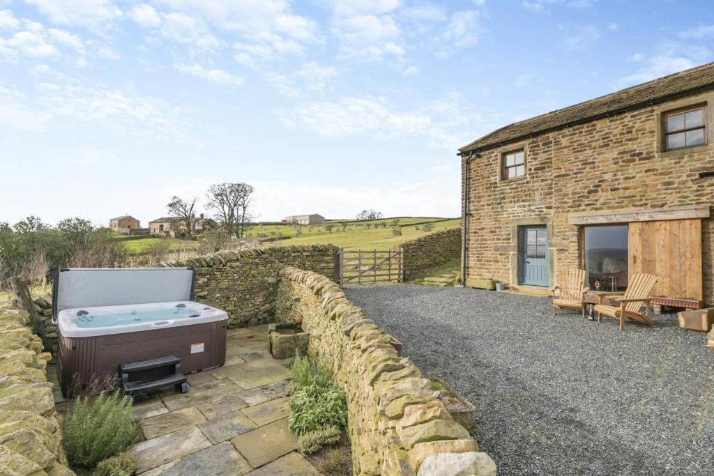a stone house with a hot tub and a stone wall at 2 Bed in Cowling oc-l30774 in Cowling