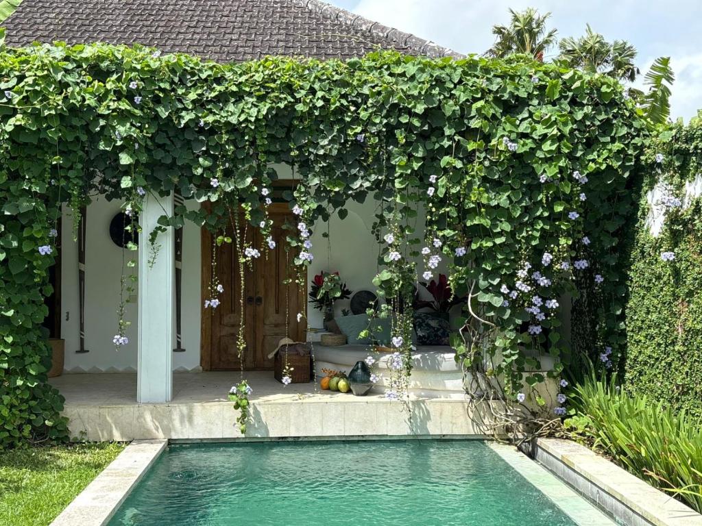 a swimming pool in a garden with a pergola at Tropical Villa Canggu Beach in Dalung