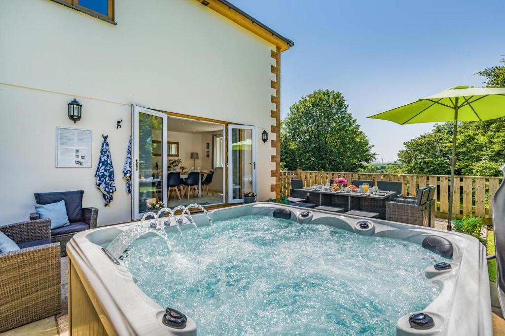 a hot tub in a backyard with an umbrella at 5 Bed in Bradworthy oc-d31987 in Bradworthy