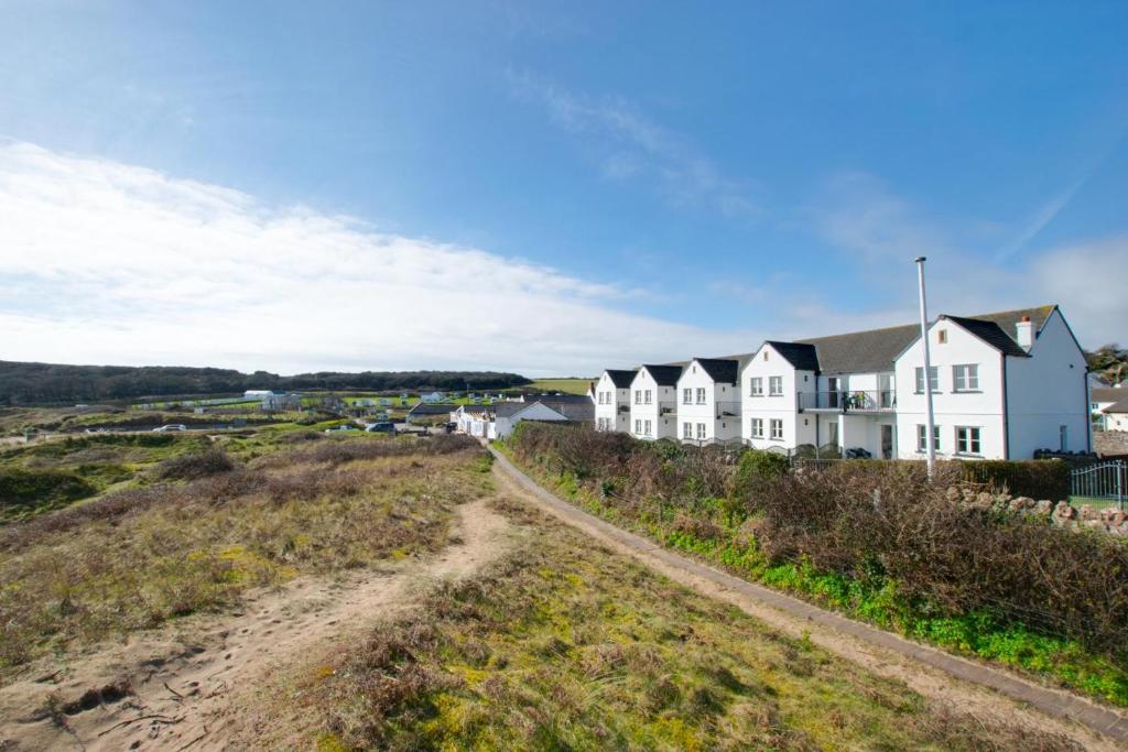 a house on the beach with a dirt road in front at 4 Bed in Gower oc-hh9906 in Port-Eynon