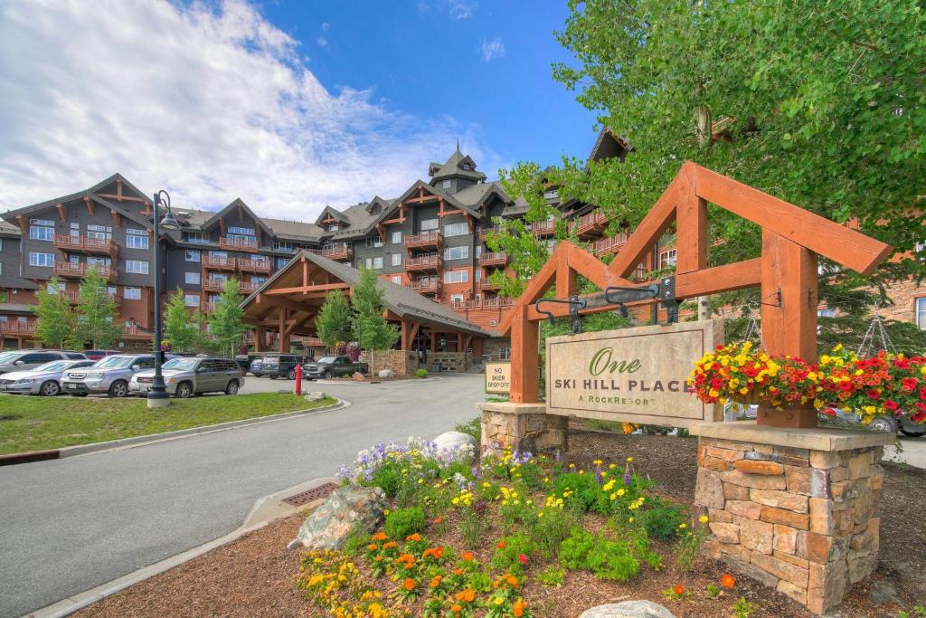 a sign in front of a apartment building with flowers at One Ski Hill Place, a RockResort, by Vail Resorts in Breckenridge