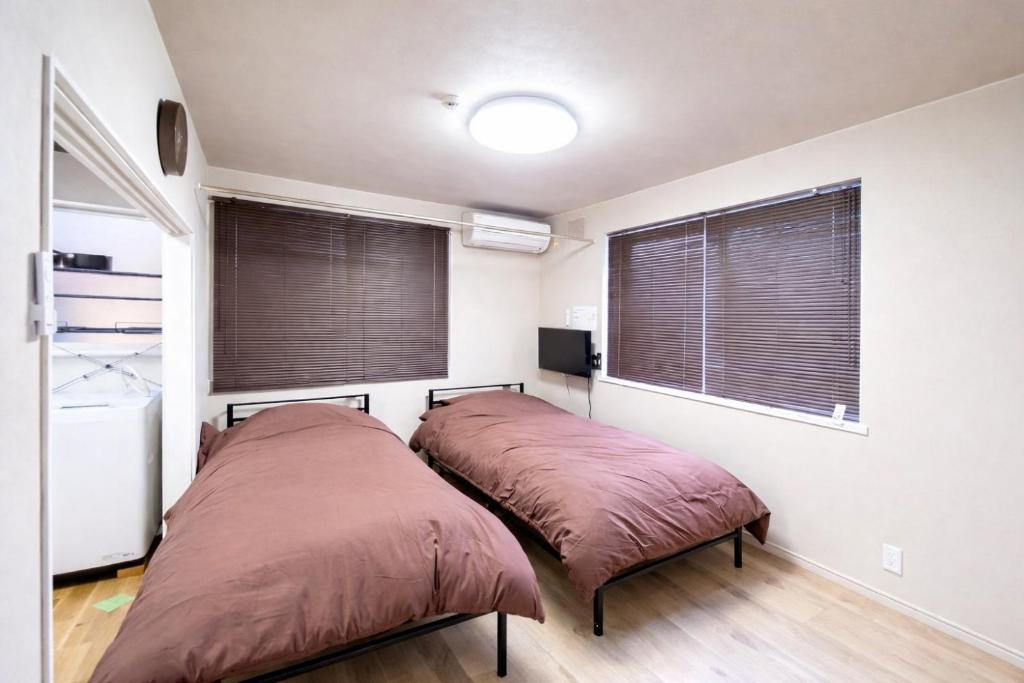 two beds in a room with two windows at シーシャイン北金沢 102号室 in Aomori