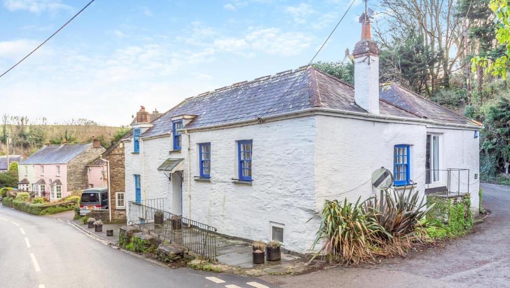 an old white house with blue windows on a street at 5 Bed in Little Petherick oc-melynw in Little Petherick