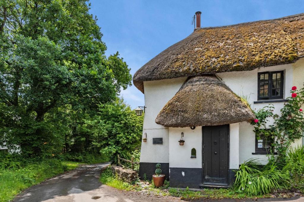 athatched cottage with a thatched roof on a road at 2 Bed in Broadwoodkelly oc-j31818 in Broadwoodkelly
