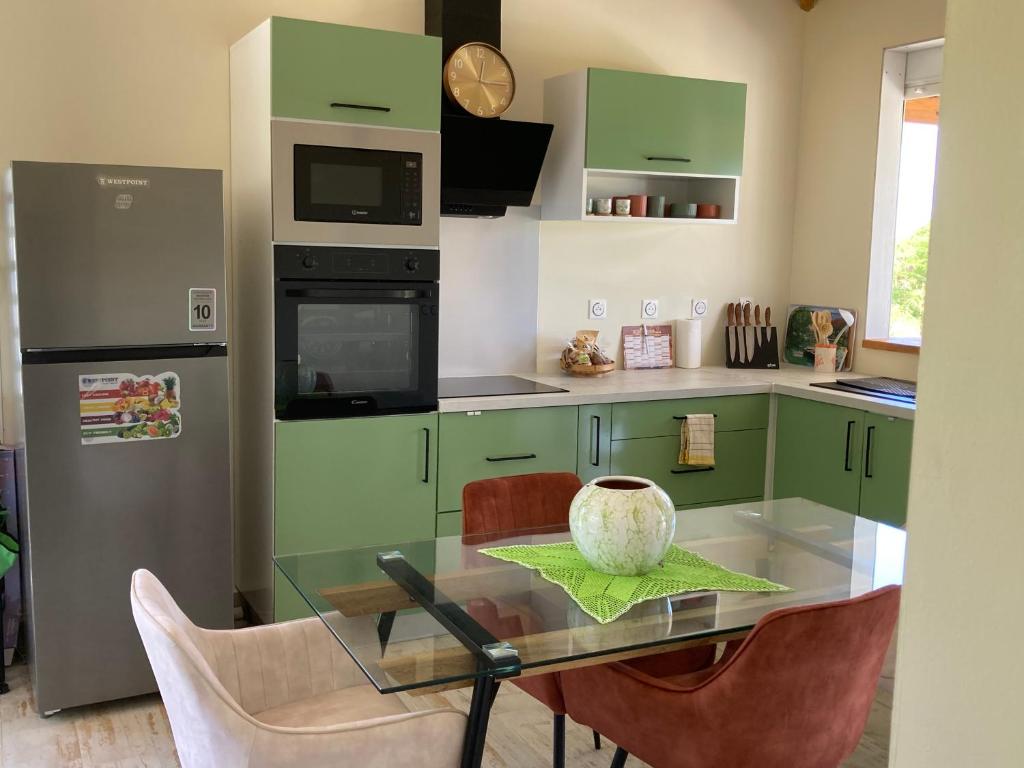 a kitchen with green cabinets and a glass table with chairs at Villa Surette in Capesterre