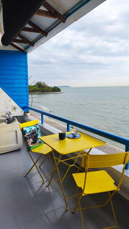 a yellow table and two chairs on a balcony overlooking the ocean at SunsetSpa PD in Port Dickson