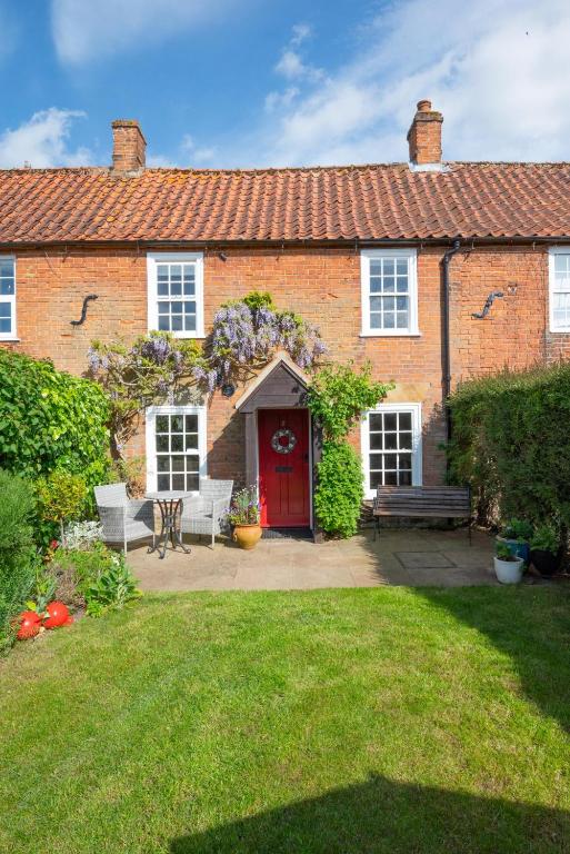 a brick house with a red door and a yard at 2 Bed in Docking oc-913 in Docking